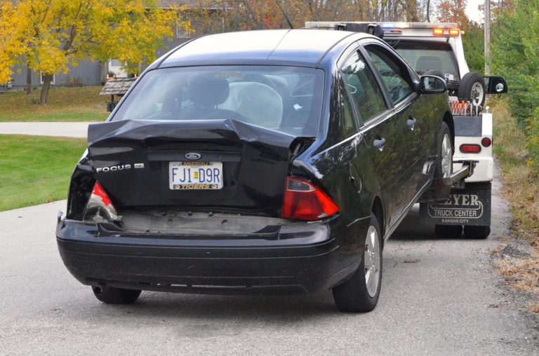 Wheel Lift Tow Truck Servicing A Black Sedan